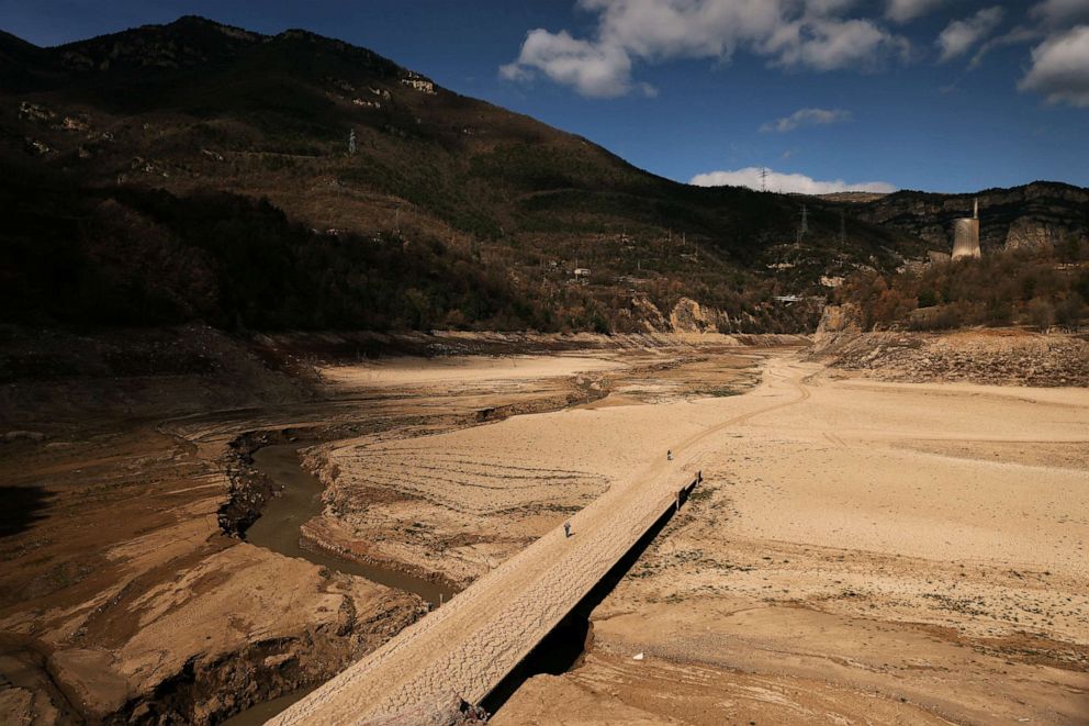 PHOTO: People walk on the cracked ground of the Baells reservoir as drinking water supplies have plunged to their lowest level since 1990 due to extreme drought in Catalonia, in the village of Cersc, Spain, March 14, 2023.