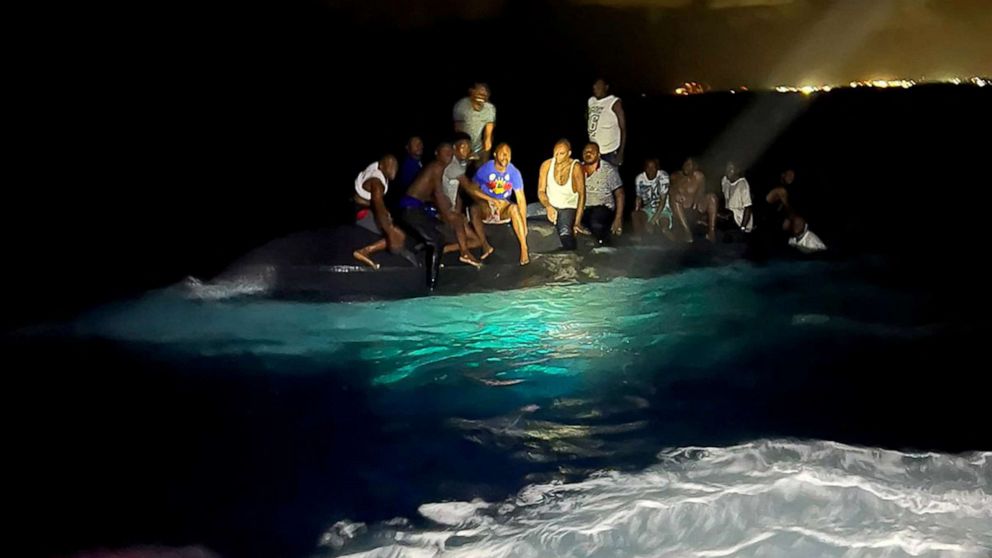 PHOTO: Survivors of a migrant boat that capsized perch on the overturned vessel off the coast of New Providence island, Bahamas, July 24, 2022. 
