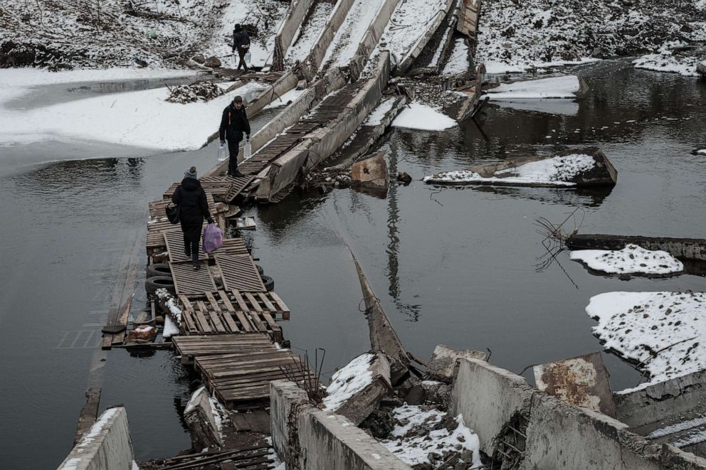 PHOTO: People walk on a destroyed bridge to cross a canal towards the disputed area in Bakhmut on Feb. 1, 2023, amid the Russian invasion of Ukraine.