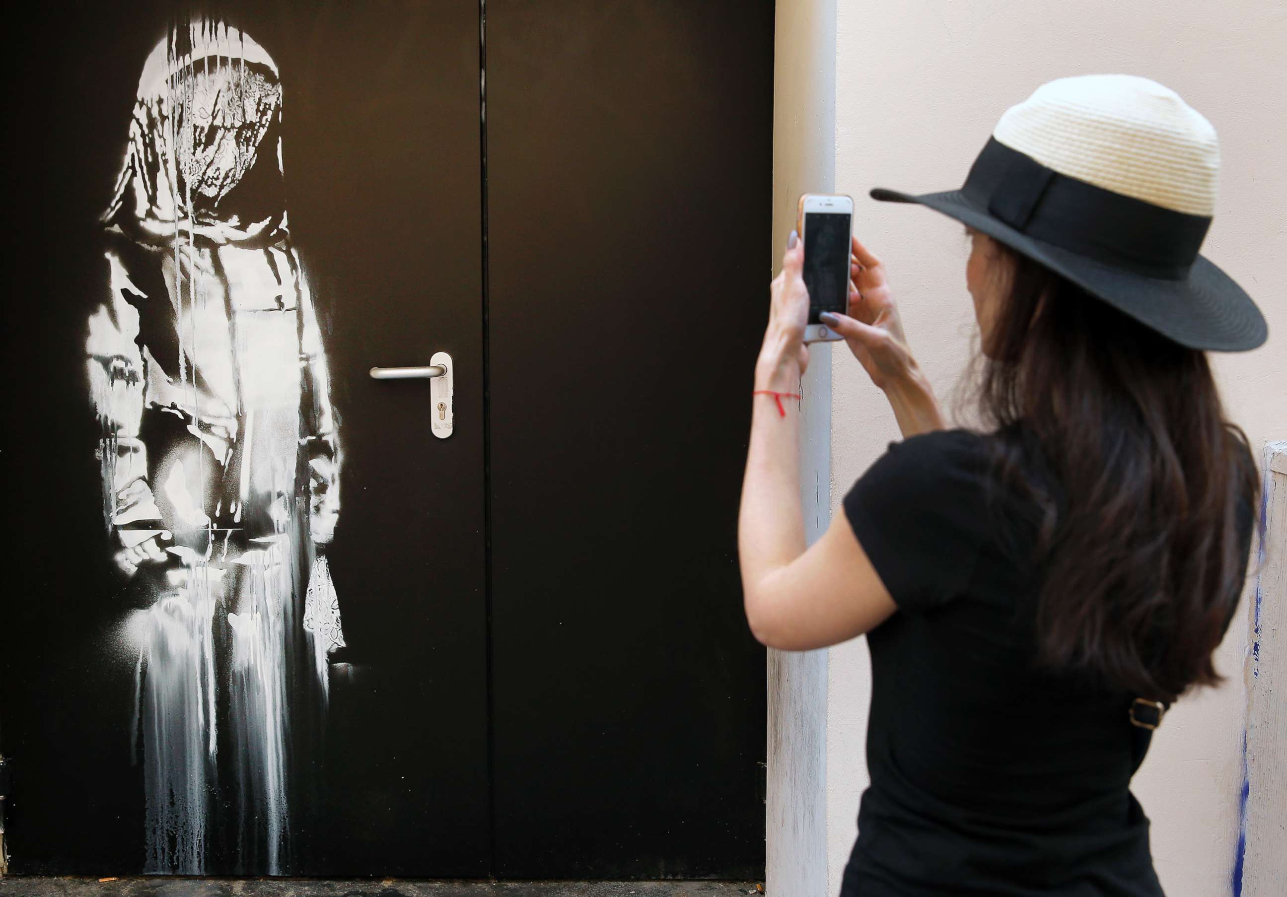PHOTO: A woman takes a picture of a recent artwork attributed to street artist Banksy on June 26, 2018, in Paris.