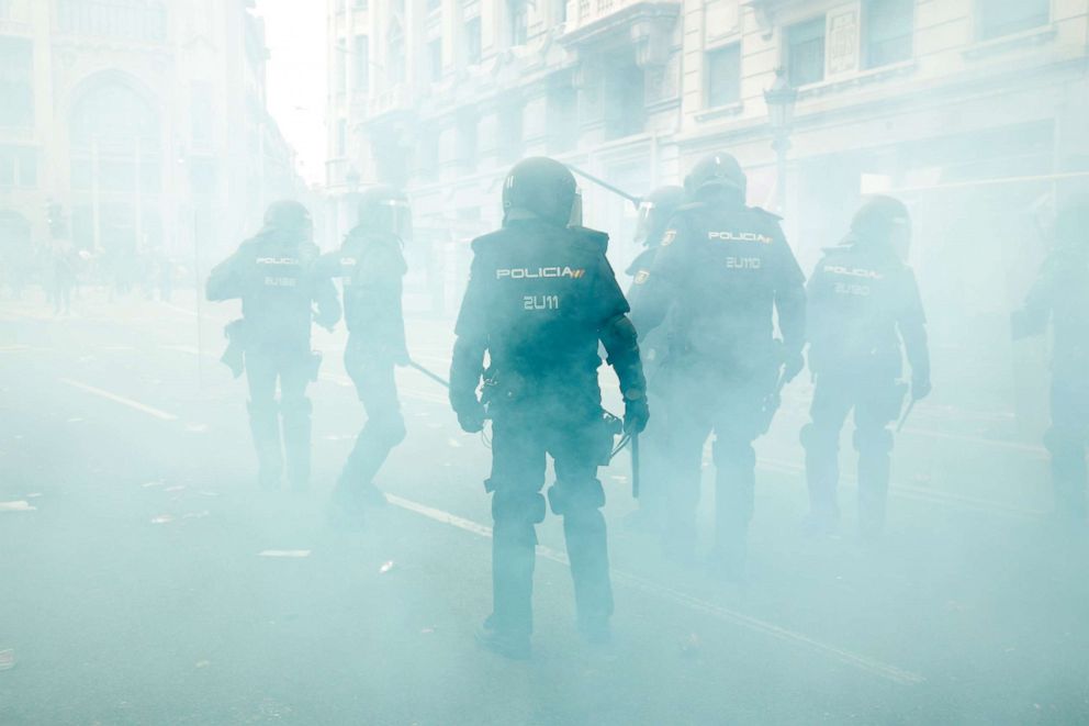 PHOTO: Spanish national police officers stand in the smoke as they protect the Police headquarters in Barcelona, on October 18, 2019, on the day that separatists have called a general strike and a mass rally.