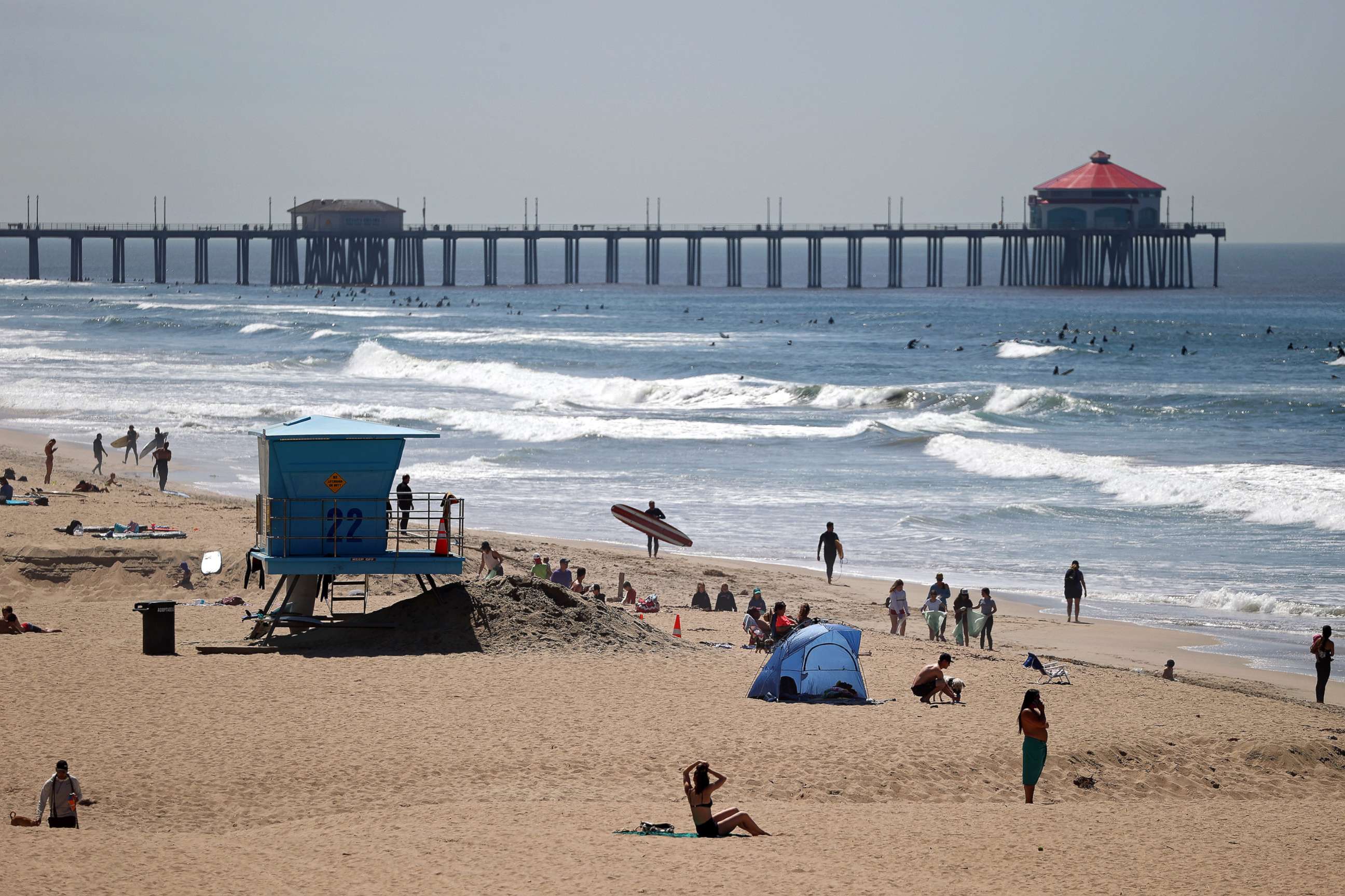 PHOTO: Beachgoers and surfers are seen at Huntington Beach, on April 22, 2020 in California. Southern California is expecting summer like weather over the next week as social distancing and beach closures continue due to the coronavirus (COVID-19). 