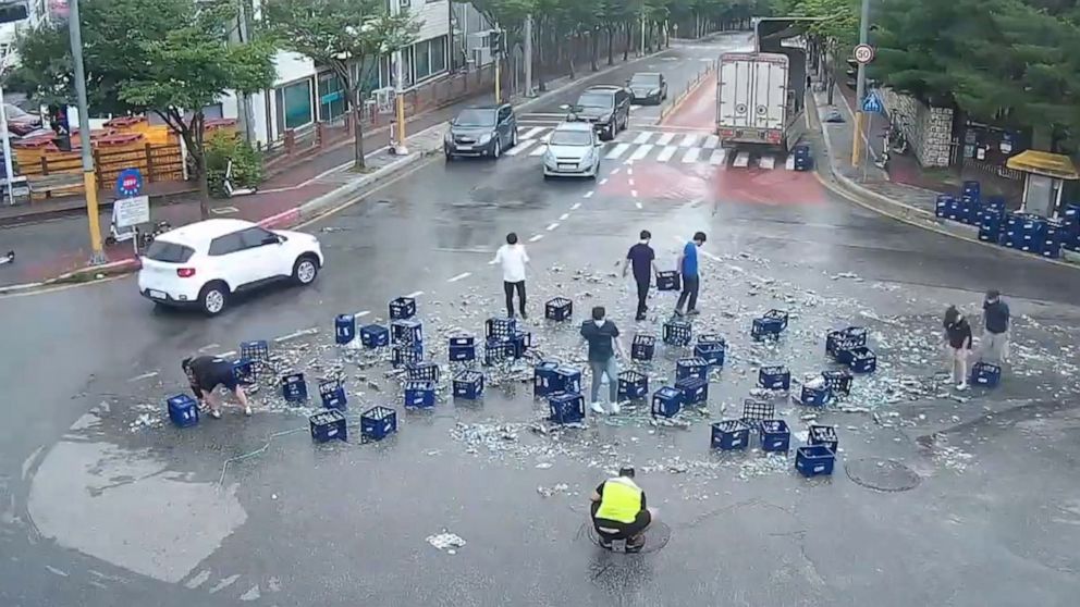 PHOTO: People help clean up bottles of beer that fell off a truck as the driver made a sharp turn in Chuncheon, South Korea, June 29, 2022.