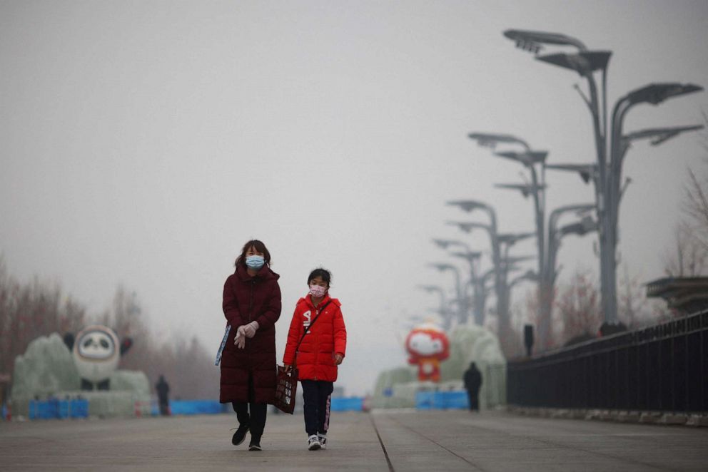 PHOTO: People walk near the closed loop "bubble" surrounding venues of the Beijing 2022 Winter Olympics on a hazy day in Beijing, China, Jan. 24, 2022.