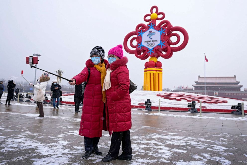 PHOTO: Women wearing face masks printed with a slogan for the Beijing Winter Olympics Games take a selfie with a decoration for the Winter Olympics Games in Tiananmen Square in Beijing, on Jan. 20, 2022.