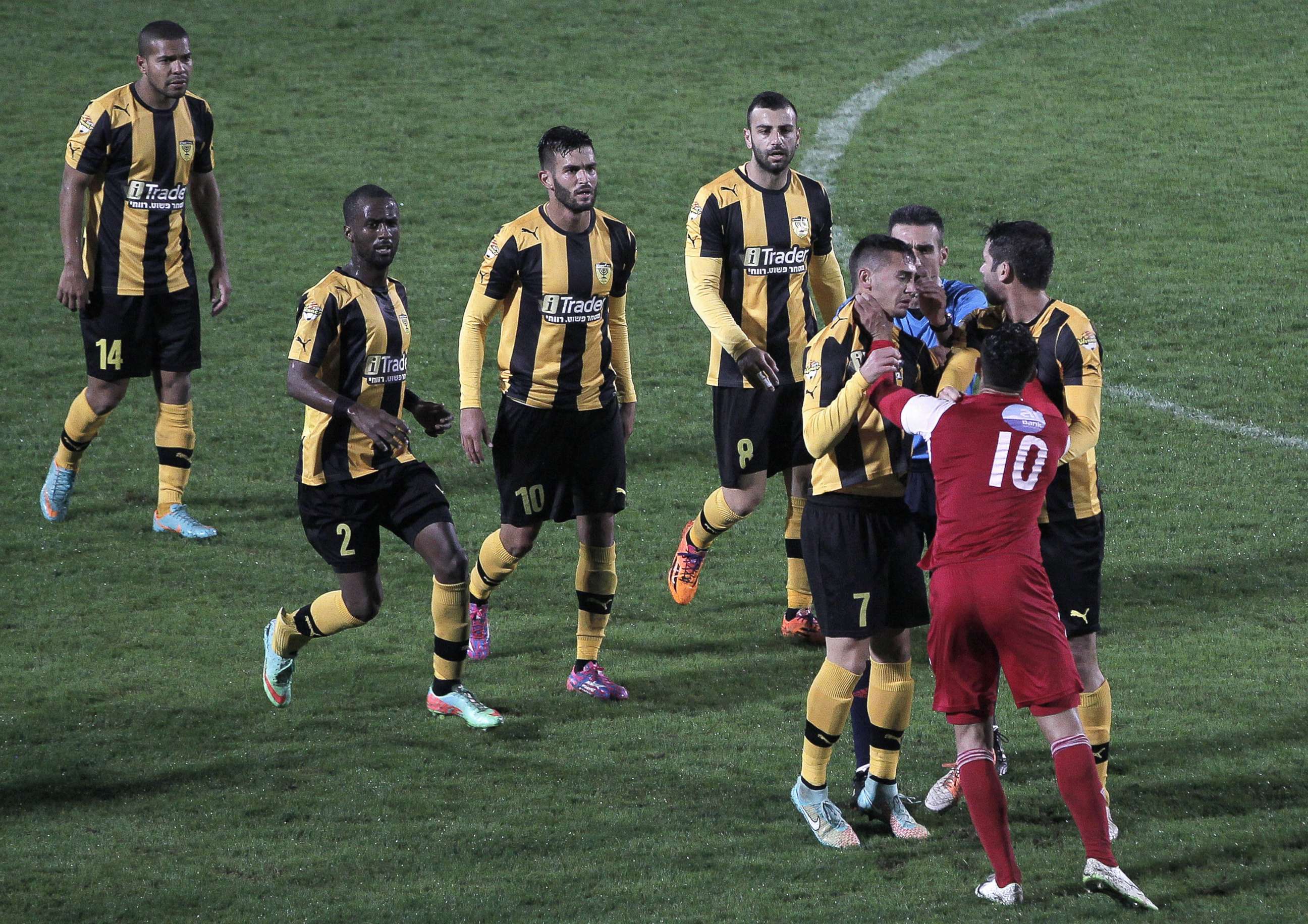 PHOTO: A player from Bnei Sakhnin, the only Arab team in the Israeli Premier league, scuffles with a player from Beitar Jerusalem at the Doha Stadium in the northern Arab-Israeli town of Sakhnin on Nov. 23, 2014.