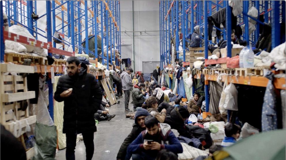 PHOTO: People are living among the shelf stacks in the warehouse, with whole families packed into the spaces where goods would normally be stored. 