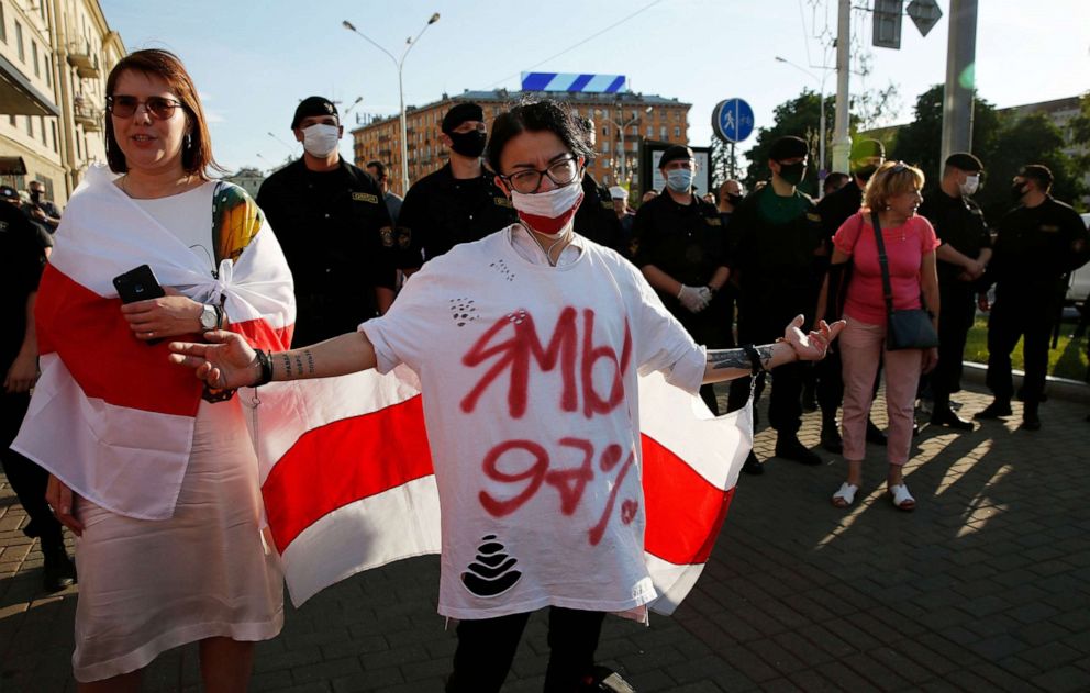 PHOTO: Hanna Kanapatskaya, left,a possible candidate in Belarus' 2020 presidential elections,and a protester in a T-shirt reading "Me You 97%" are covered in white-red-white flags during a rally in Minsk, Belarus,June 19, 2020.