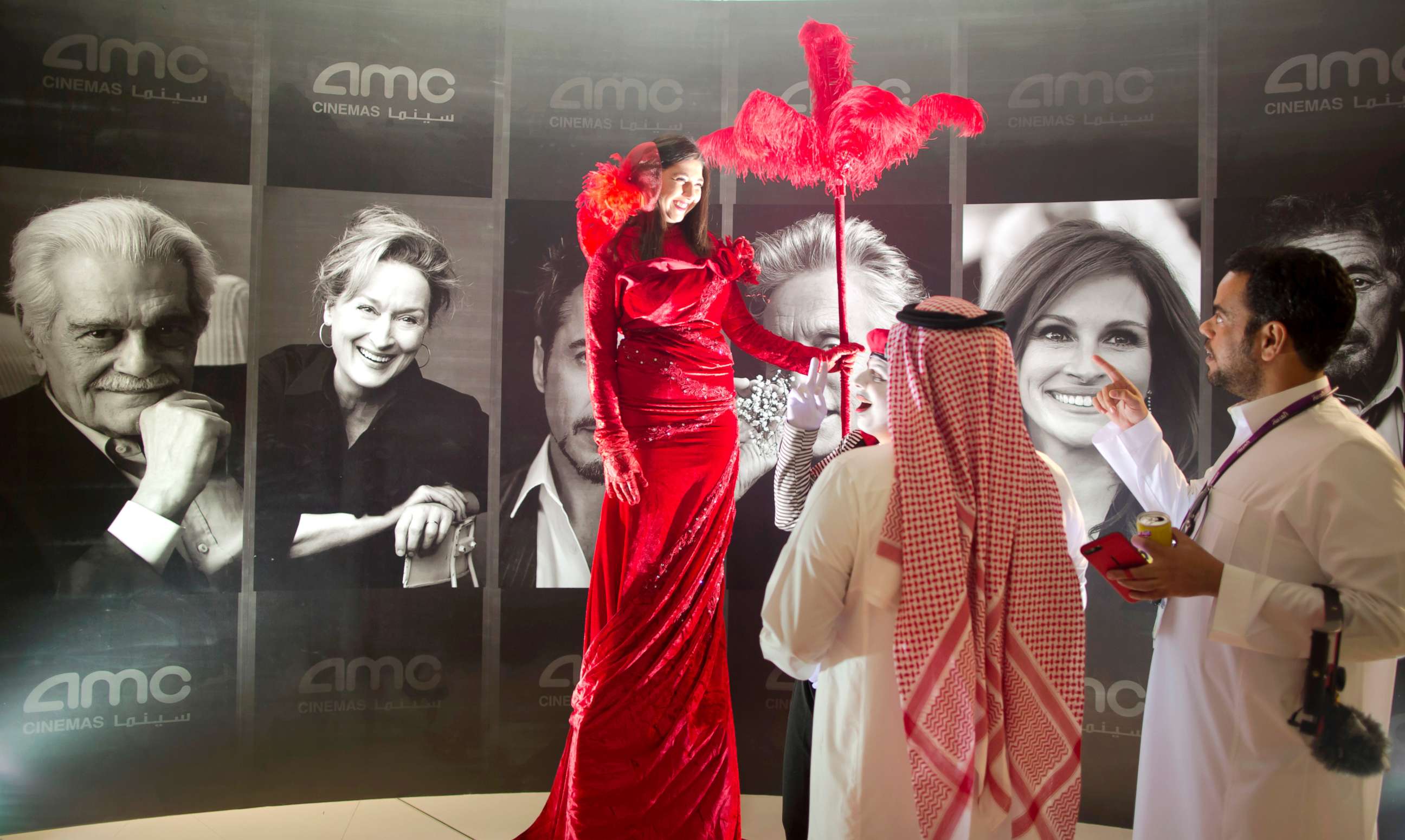 PHOTO: Visitors chat with an actress in front of posters of Hollywood stars during invitation-only screening, at the King Abdullah Financial District Theater, in Riyadh, Saudi Arabia, April 18, 2018.