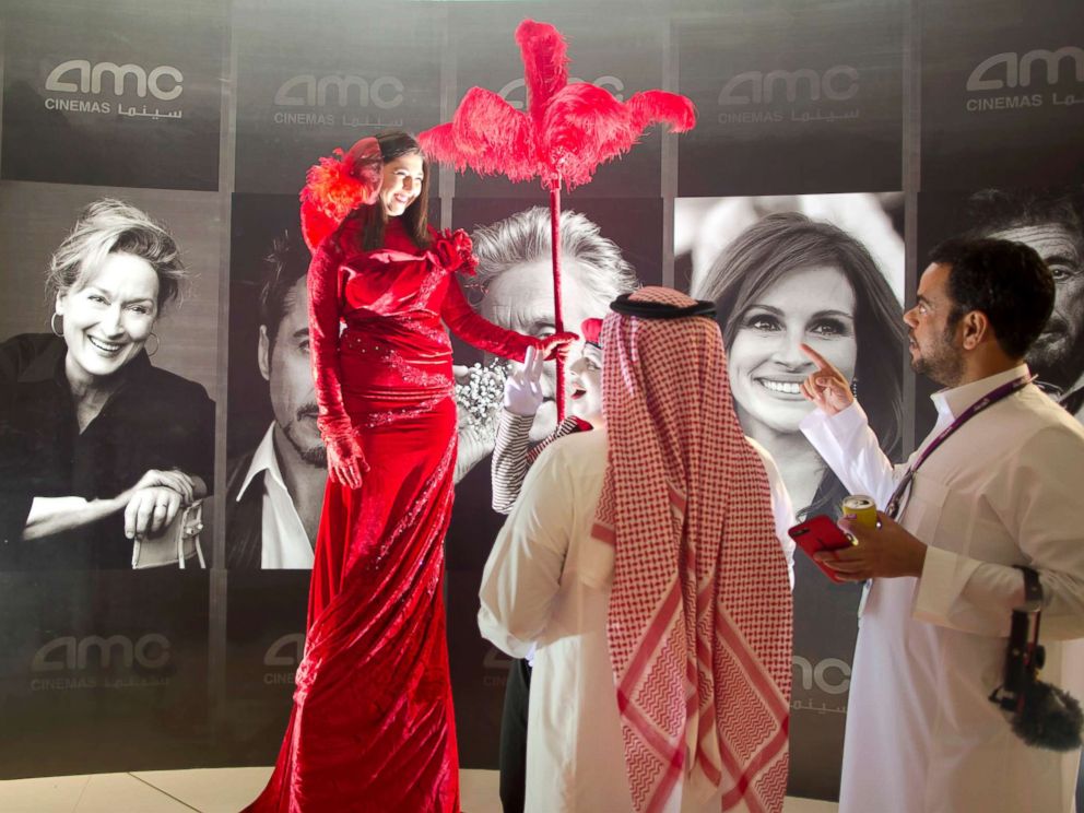 PHOTO: Visitors chat with an actress in front of posters of Hollywood stars during invitation-only screening, at the King Abdullah Financial District Theater, in Riyadh, Saudi Arabia, April 18, 2018.