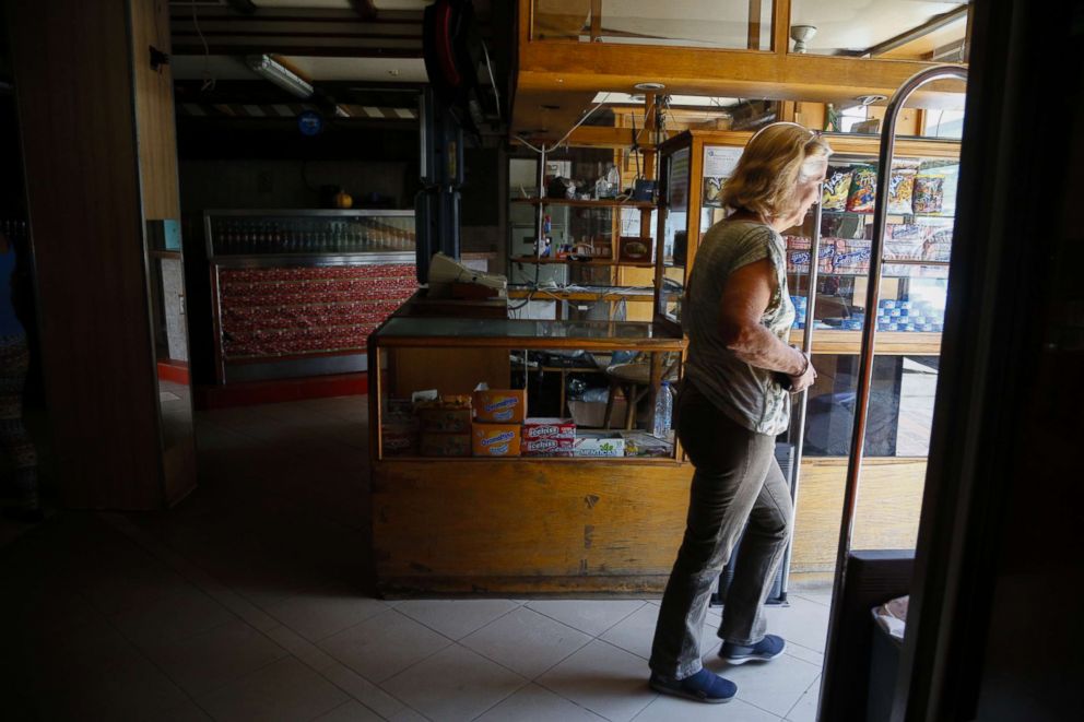 PHOTO: A woman leaves a grocery store with no power during blackouts, March 12, 2019 in Caracas, Venezuela