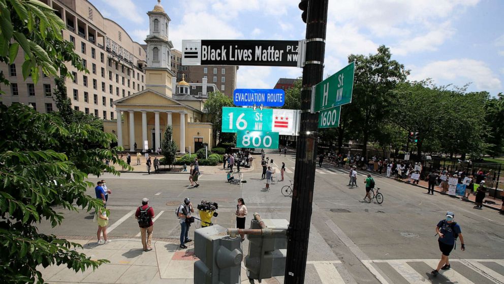 PHOTO: With St. John's Church in the background, people walk under a new street sign, June 5, 2020, in Washington.