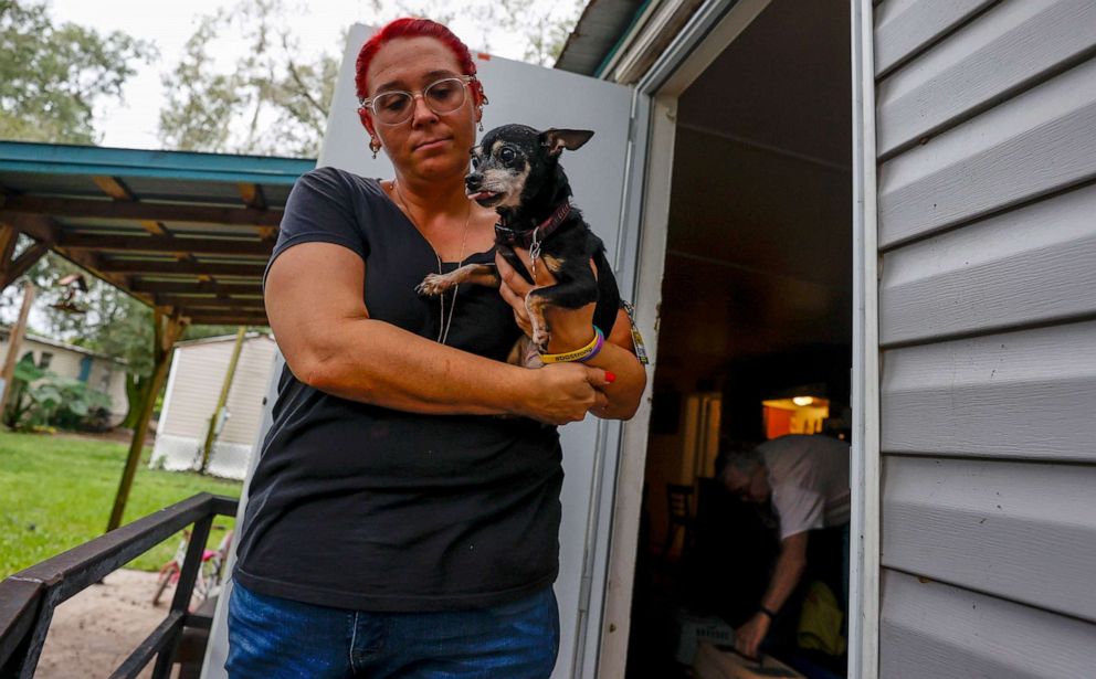PHOTO: Heather Silke, 35, carries Nugget, the family's 16-year-old Chihuahua, as they evacuate from their home to shelter with family friends in Riverview before Hurricane Ian makes landfall in Tampa, Fla., Sept. 27, 2022.