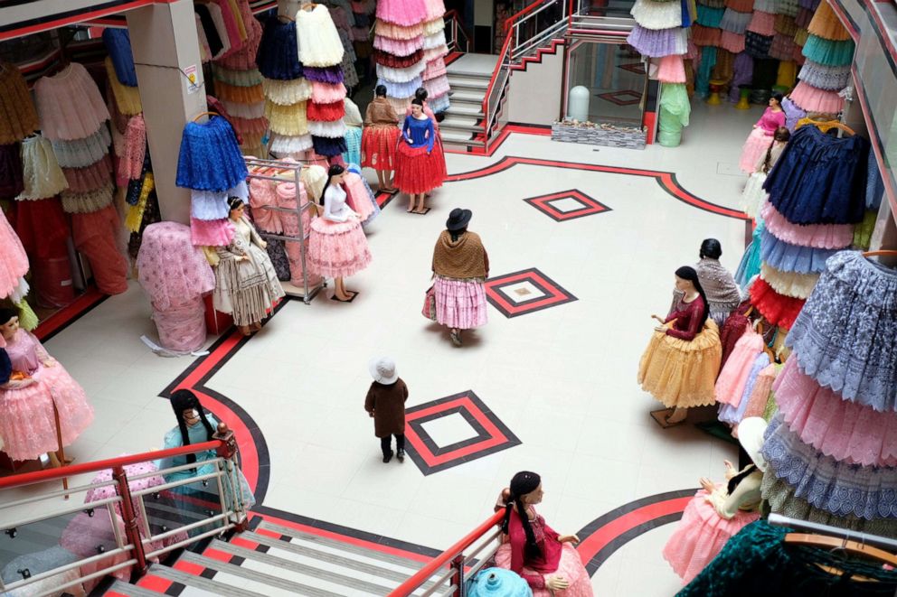 PHOTO: A cholita walks through a newly opened gallery in the 16 de Julio fair in El Alto, Bolivia, October 3, 2019. The 16 de Julio fair is one of the biggest open street markets in the world, with hundreds of street stores and galleries.