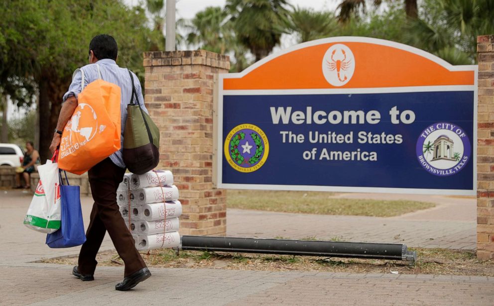 PHOTO: A pedestrian carries supplies as he enters Texas after crossing over from Mexico at the Gateway International Bridge, March 20, 2020, in Brownsville, Texas.