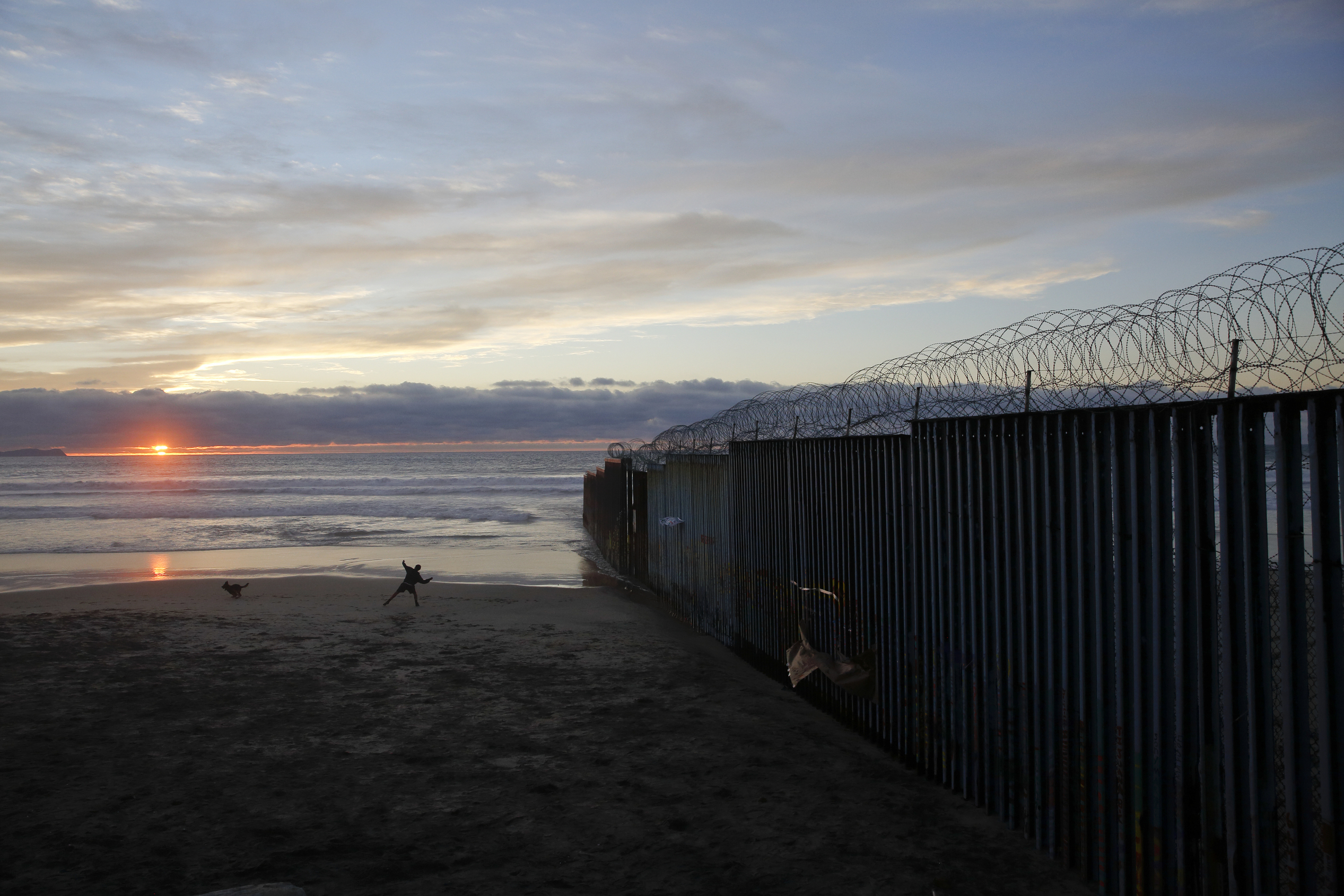 PHOTO: In this Jan. 9, 2019, file photo, a man throws a ball for his dog next to the border wall topped with razor wire in Tijuana, Mexico. 