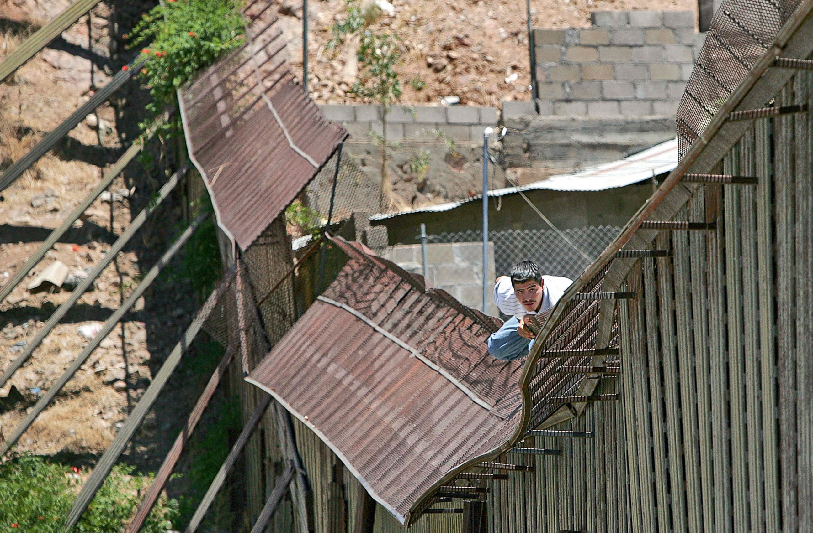 PHOTO: In this May 31, 2006, file photo, a man climbs over the international border into Nogales, Ariz., from Nogales, Mexico.