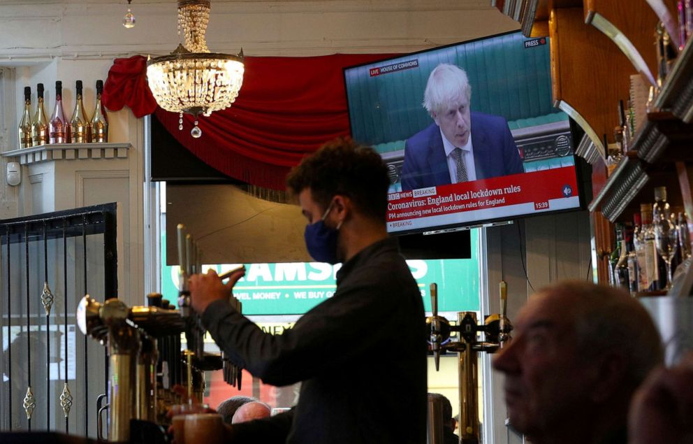 PHOTO: A member of staff pours a drink in The Richmond Pub in Liverpool, England, as the TV screen shows British Prime Minister Boris Johnson delivering a statement from the House of Commons on Oct. 12, 2020.