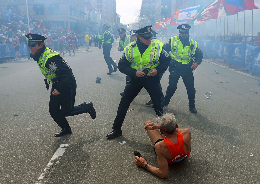 PHOTO: Police officers with their guns drawn hear the second explosion down the street. The first explosion knocked down 78-year-old US marathon runner Bill Iffrig at the finish line of the 117th Boston Marathon, April 15, 2013.