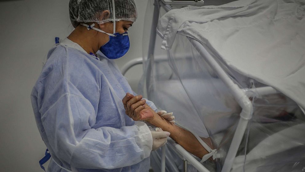 PHOTO: A nurse holds the arm of a patient infected by COVID-19 at the Gilberto Novaes Municipal Field Hospital, on May 21 2020, in Manaus, Brazil.