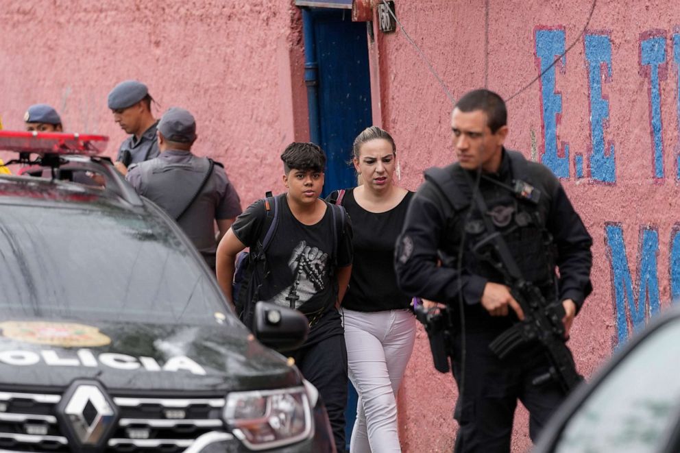 PHOTO: A student leaves the Thomazia Montoro school with his mother, as they walk past security forces, after a fatal stabbing at the school in Sao Paulo, Brazil, March 27, 2023.