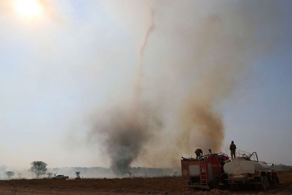 PHOTO: Firefighters from the State of Mato Grosso fill their truck with water as they prepare to extinguish a fire in front of a smoke funnel, on a farm in the Pantanal, the world's largest wetland, in Pocone, Mato Grosso state, Brazil, Aug. 28, 2020.