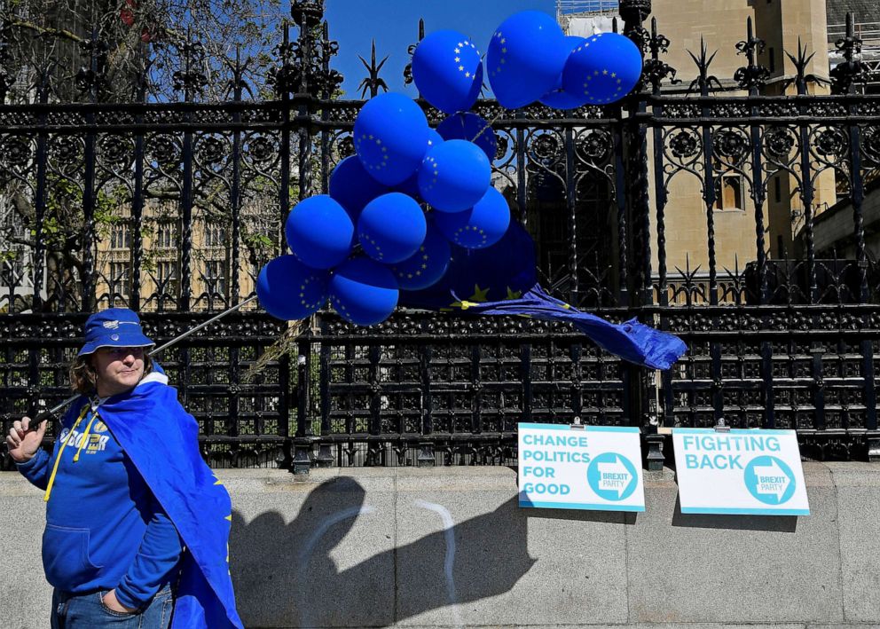 PHOTO: An anti-Brexit protester stands next to Brexit Party campaign placards outside of the Houses of Parliament in London, May 16, 2019.