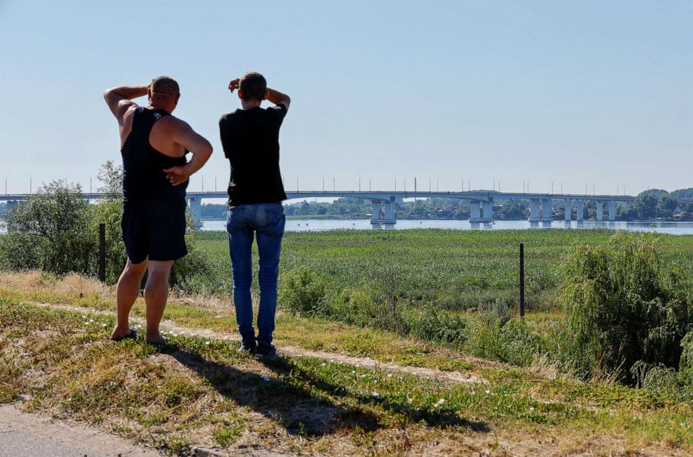 PHOTO: Men look at the Antonivskiy bridge closed for civilians, after it reportedly came under fire during Ukraine-Russia conflict in the Russian-controlled city of Kherson, Ukraine, July 27, 2022.