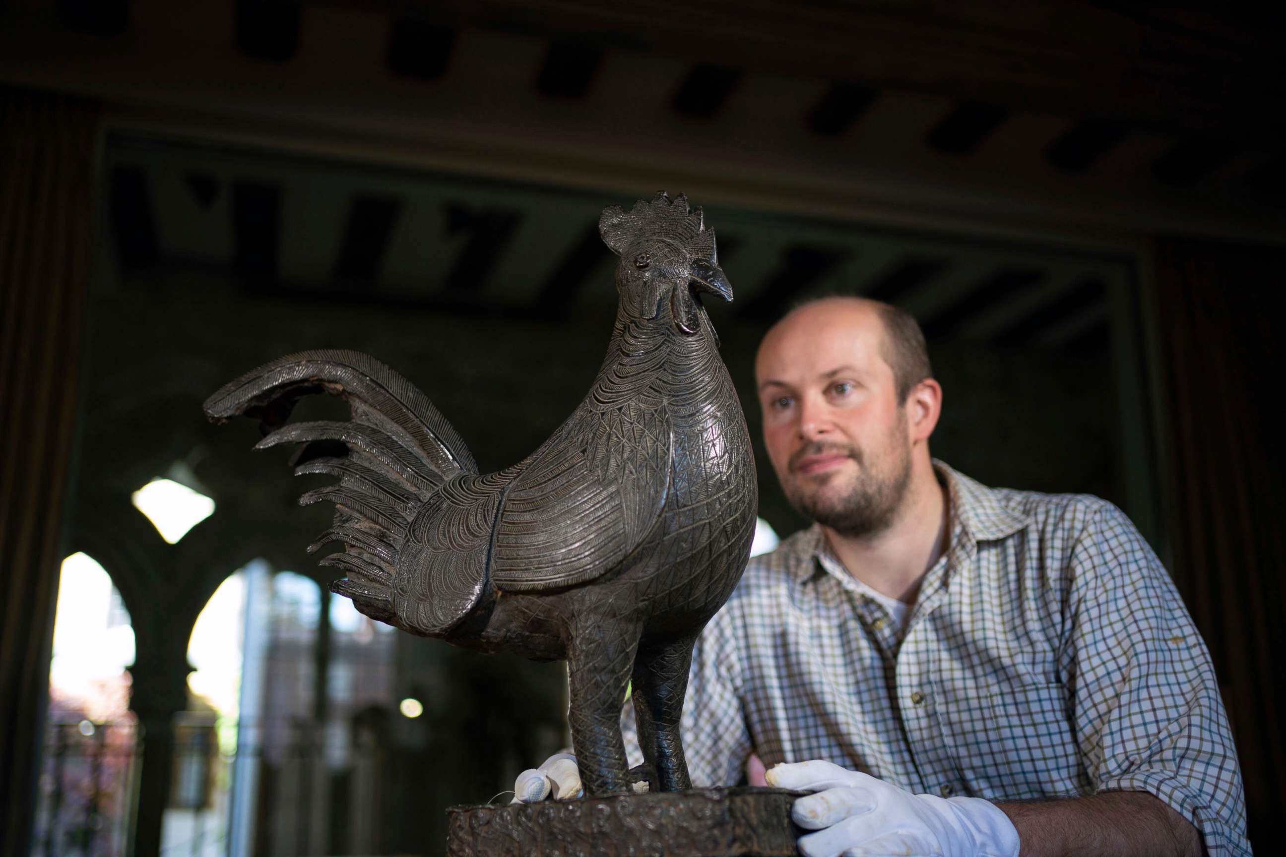 PHOTO: Archivist Robert Athol looks at a bronze statue of a cockerel called The Okukor, at Jesus College, University of Cambridge, England, Oct. 15, 2021.