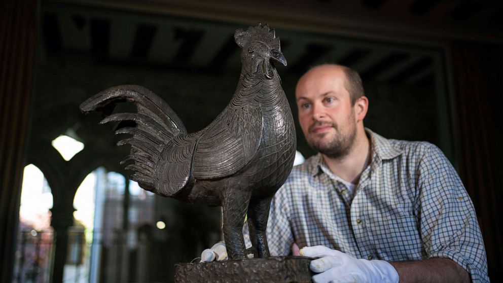PHOTO: Archivist Robert Athol looks at a bronze statue of a cockerel called The Okukor, at Jesus College, University of Cambridge, England, Oct. 15, 2021.