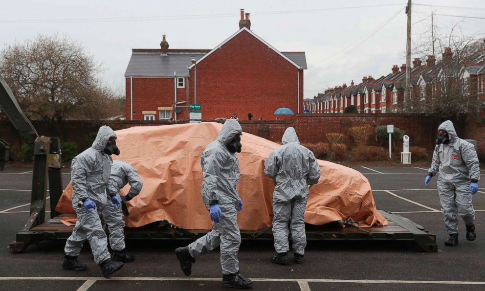 PHOTO: Military personnel wearing protective coveralls load a police car onto a military vehicle for it to be taken away from a cordoned off area behind a police station in Salisbury, England, on March 11, 2018.