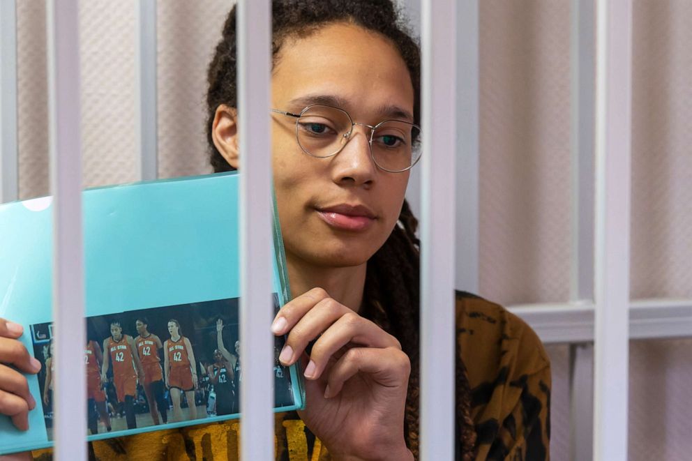 PHOTO: WNBA star and two-time Olympic gold medalist Brittney Griner holds up a photo of players from the all star game wearing her number, while sitting in a cage in court prior to a hearing, just outside Moscow, July 15, 2022.