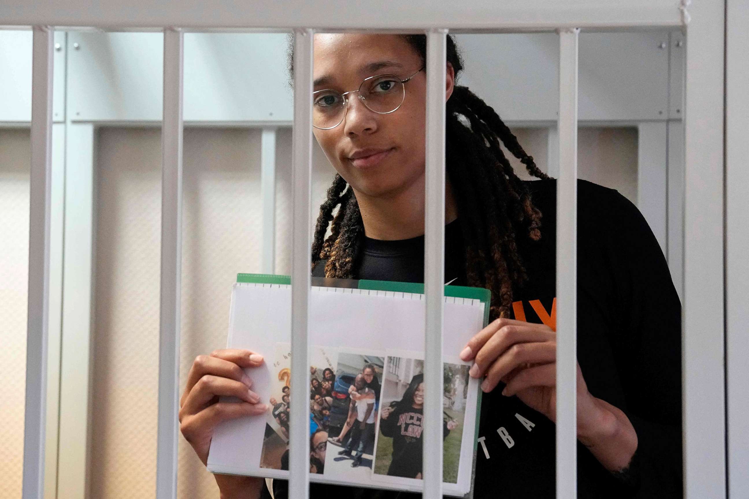 PHOTO: Olympian and WNBA basketball superstar Brittney Griner holds photographs standing inside a defendants' cage before a hearing at the Khimki Court, outside Moscow on July 27, 2022.