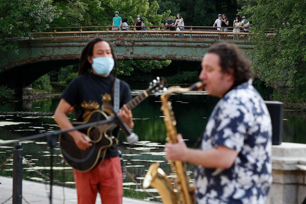 PHOTO: People watch from the Lullwater Bridge in Brooklyn's Prospect Park in New York as Alegba Jahyile, left, and Mark Kraszewski play as part of Alegba and Friends' free nightly outdoor concerts in New York City, June 18, 2020.