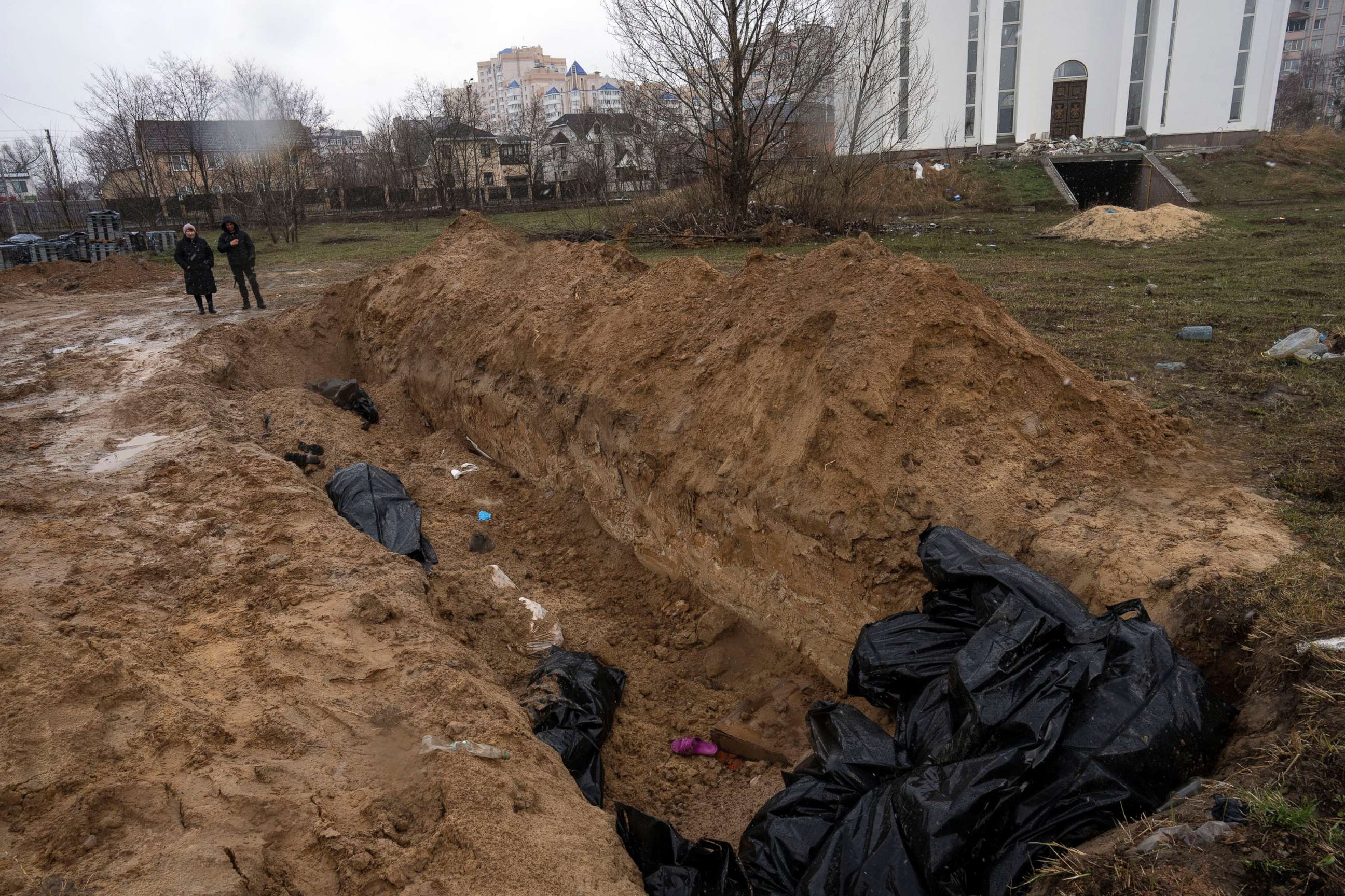 PHOTO: Neighbors gather next to a mass grave near the Church of St. Andrew and Pyervozvannoho All Saints in Bucha, on the outskirts of Kyiv, Ukraine, April 3, 2022.