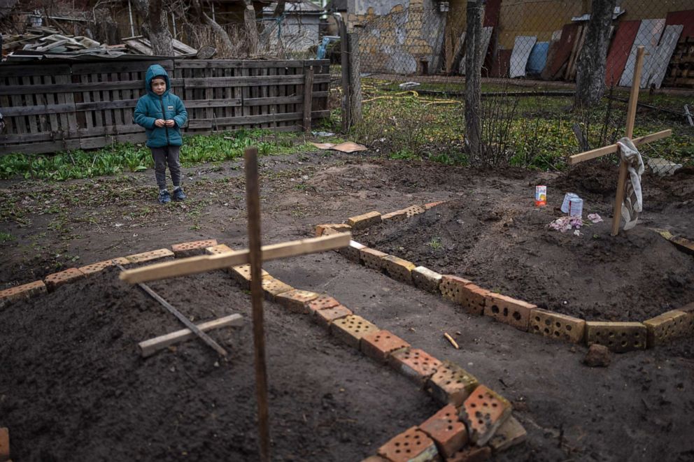 PHOTO: In the courtyard of their house, Vlad Tanyuk, 6, looks at the grave of his mother Ira Tanyuk, who died because of starvation and stress due to the war, in Bucha, Ukraine, April 4, 2022.