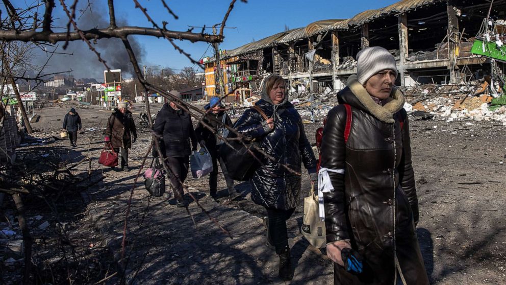 FOTOĞRAF: Şu anda Rus ordusu tarafından kontrol edilen Bucha kasabasından gelen sakinler, 1 Mart 2022, Irpin, Ukrayna'daki cephe hattındaki Ukrayna kontrol noktasına doğru bavullarıyla yürüyorlar.