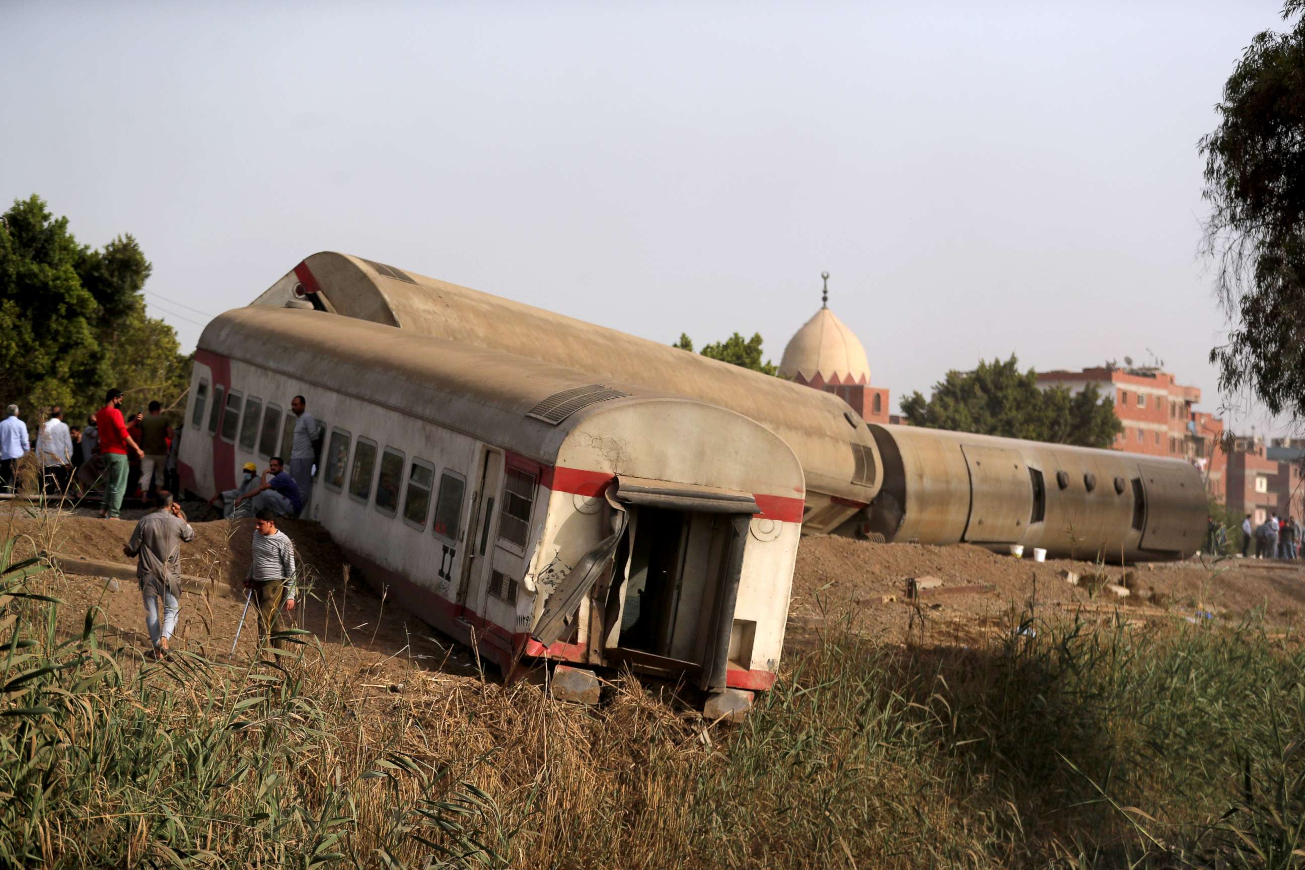 PHOTO: People gather at the site where train carriages derailed in Qalioubia north of Cairo, Egypt, April 18, 2021.