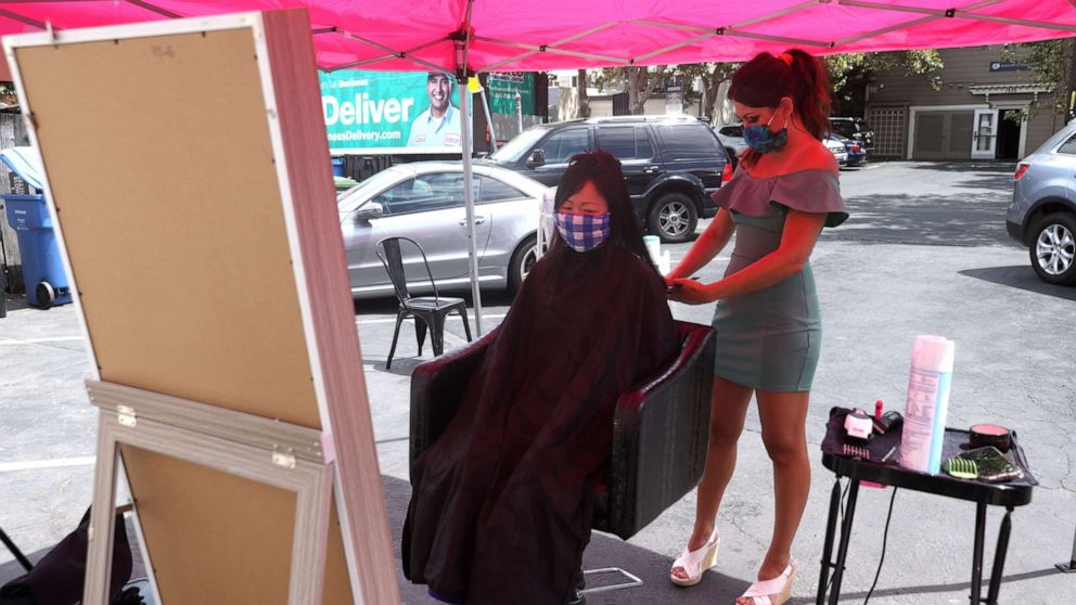 PHOTO: Insignia Hair Salon stylist Regina Muslimova gives a haircut in the parking lot behind the salon, July 21, 2020, in Walnut Creek, California.