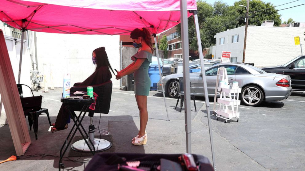 PHOTO: Insignia Hair Salon stylist Regina Muslimova gives a haircut in the parking lot behind the salon, July 21, 2020, in Walnut Creek, California.