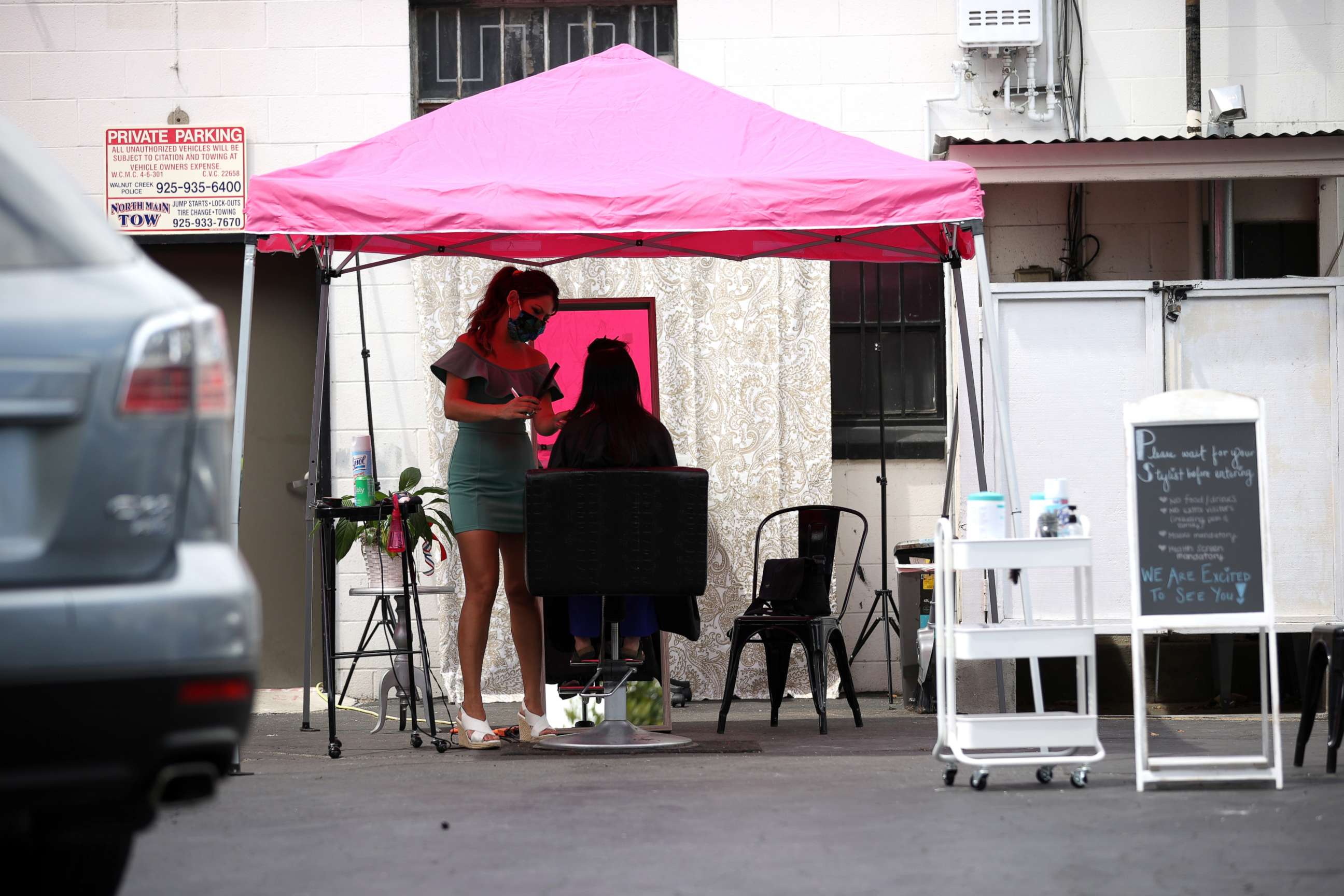 PHOTO: Insignia Hair Salon stylist Regina Muslimova gives a haircut in the parking lot behind the salon, July 21, 2020, in Walnut Creek, California.