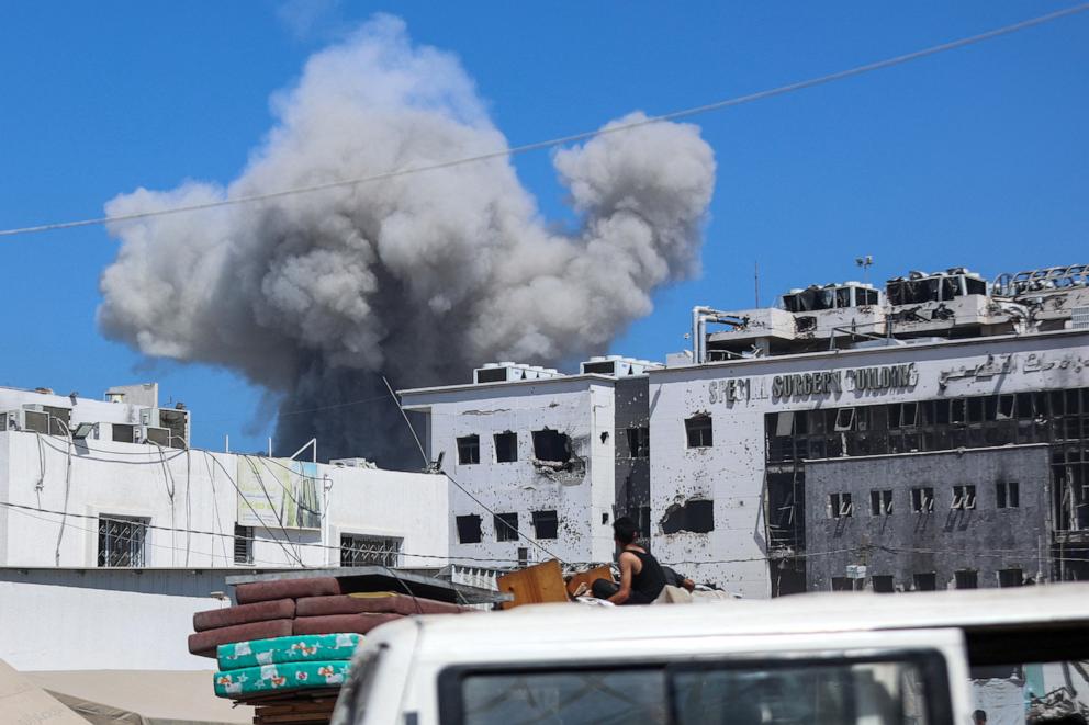 PHOTO: Displaced Palestinians sitting in the back of a truck laden with their belongings while fleeing bombardment, watch smoke billowing amid Israeli strikes on al-Shati camp for Palestinian refugees west of Gaza City on Sept. 18, 2025.