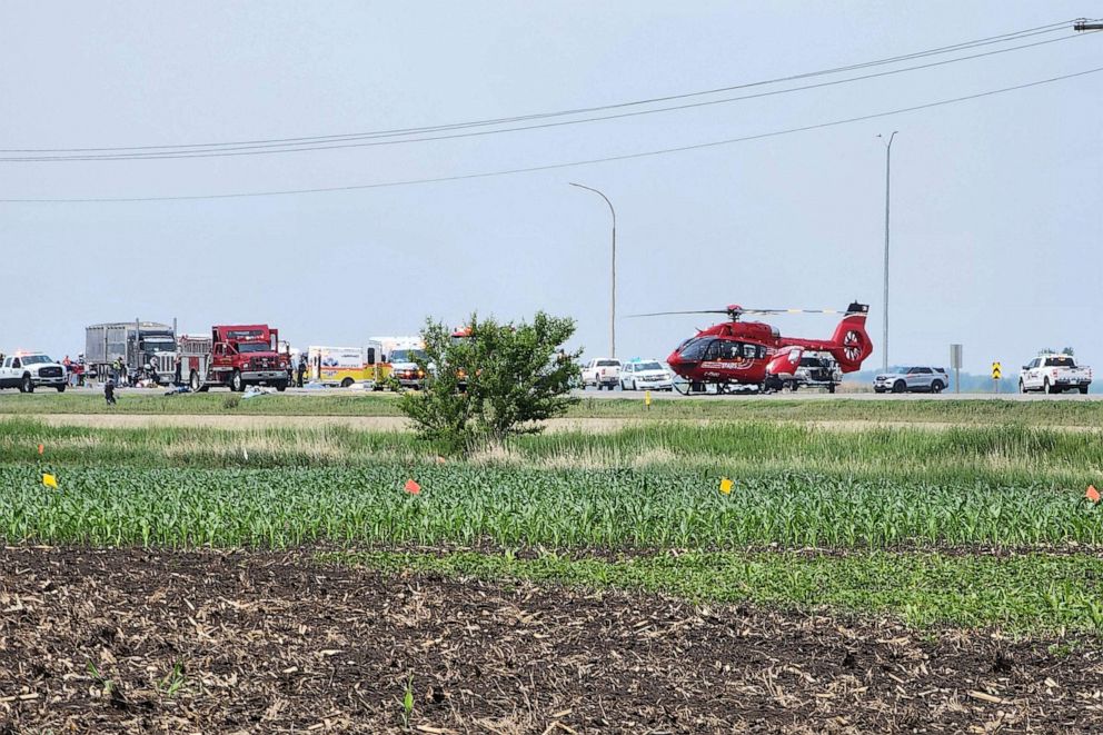 FOTO: Z vozidla se valí kouř, když první zasahující jsou na místě smrtelné dopravní nehody poblíž Carberry, západně od Winnipegu v Kanadě, 15. června 2023.
