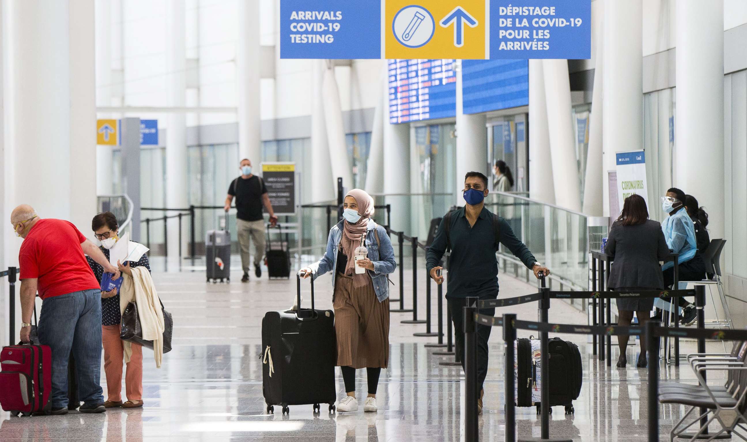 PHOTO: In this July 5, 2021, file photo, travelers wearing face masks walk out of the arrivals hall at Toronto Pearson International Airport in Mississauga, Ontario, Canada.