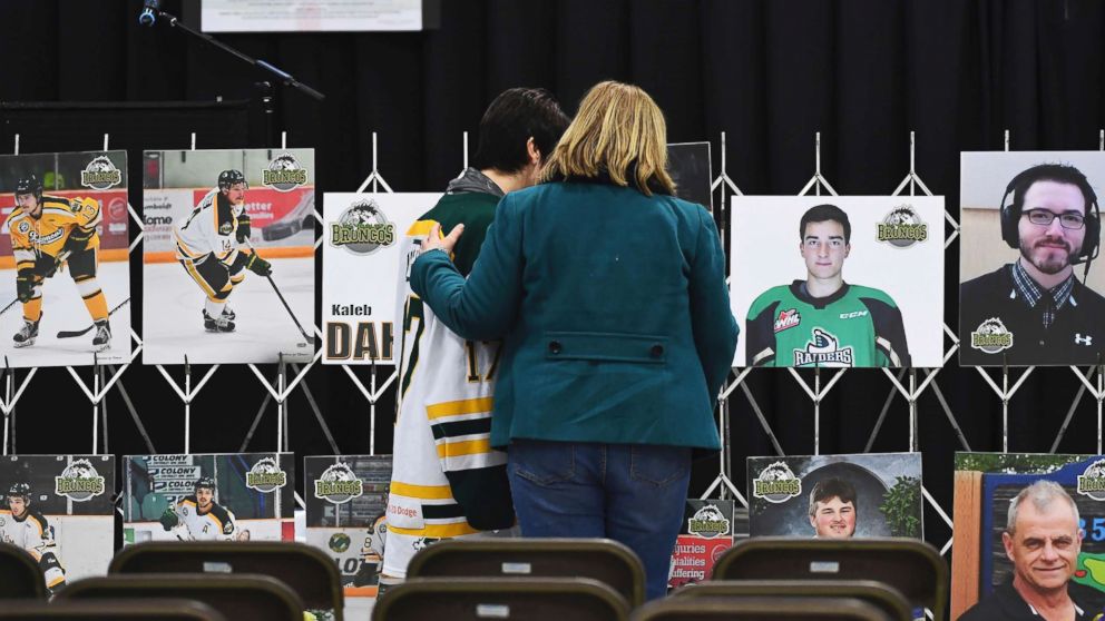 Mourners comfort each other as they look at photographs before a vigil at the Elgar Petersen Arena, home of the Humboldt Broncos, to honor the victims of a fatal bus accident in Humboldt, Canada, April 8, 2018.