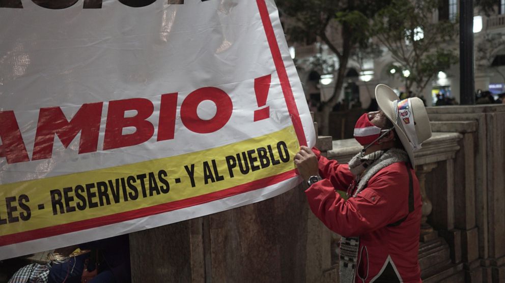 PHOTO: A supporter of Peru's far-left candidate Pedro Castillo, looks up at a sign in support as they converged on the capital to protest allegations of fraud by his opponent Keiko Fujimori.
