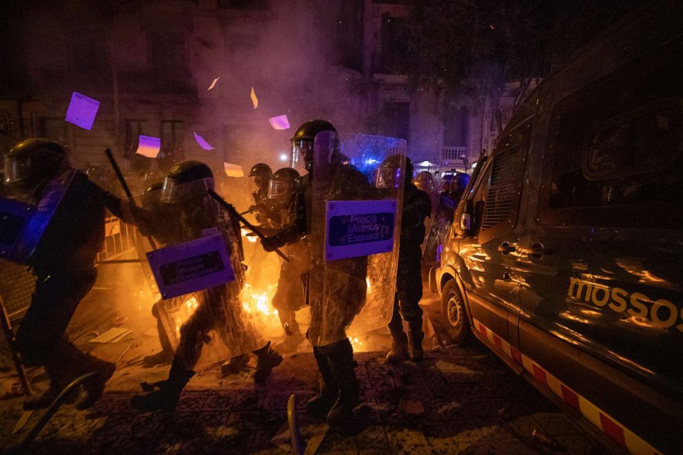 PHOTO: Policemen in riot gear move past a burning barricade during clashes with demonstrators in Barcelona, Oct. 15, 2019. 