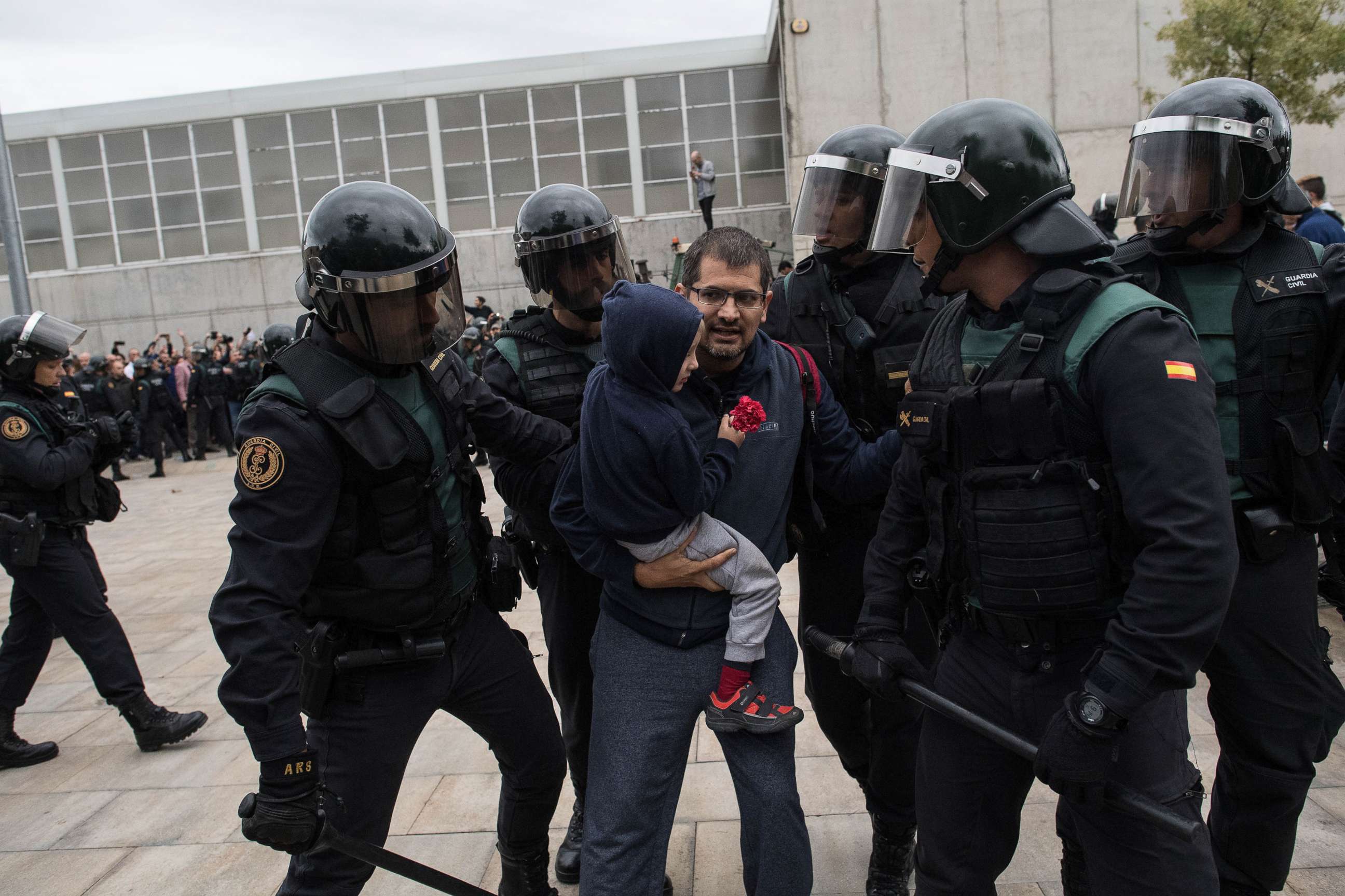 PHOTO: A man and a child holding a red flower run from the police as they move in on the crowds, Oct. 1, 2017 in Sant Julia de Ramis, Spain. 