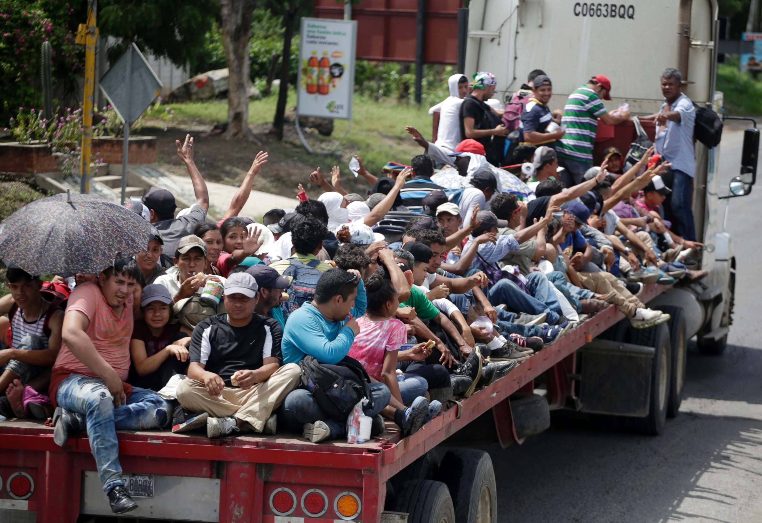 PHOTO: Honduran migrants who are traveling to the United States as a group, get a free ride in the back of a trailer truck flatbed, as they make their way through Teculutan, Guatemala, Oct. 17, 2018.
