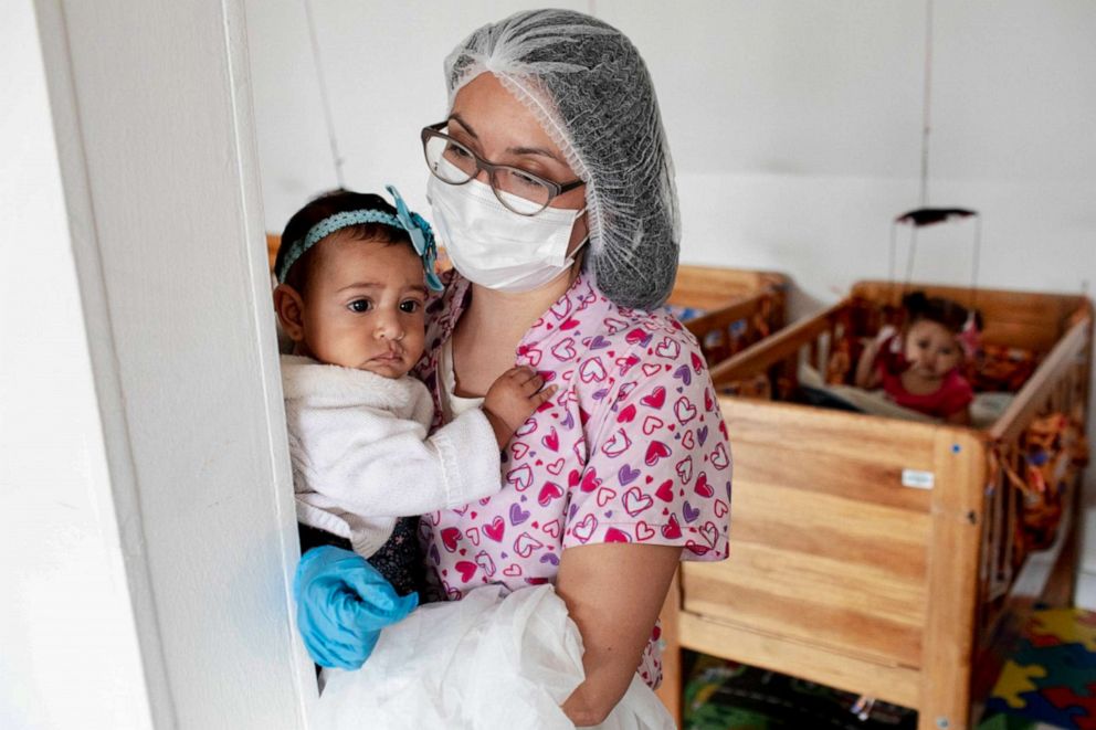 PHOTO: A staff member carries a young girl at El Centro Abrazar in Bogota, Jan. 20, 2020.